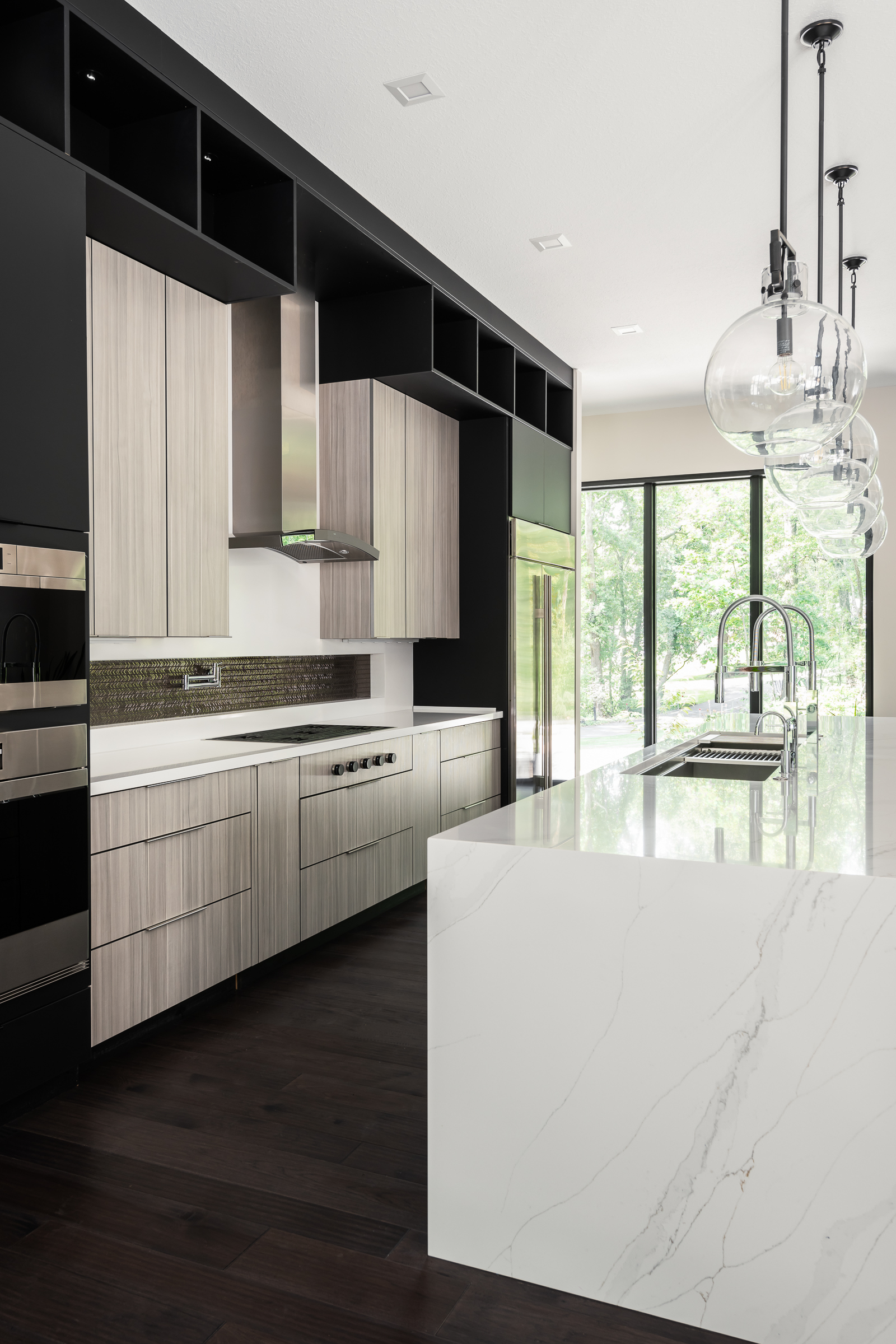 Modern details in this open concept kitchen include frameless cabinets, a waterfall top and concealed appliances